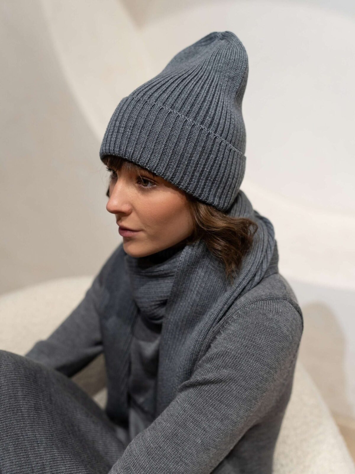 Grey ribbed beanie hat in merino wool. Paired with a matching scarf and a turtleneck dress.