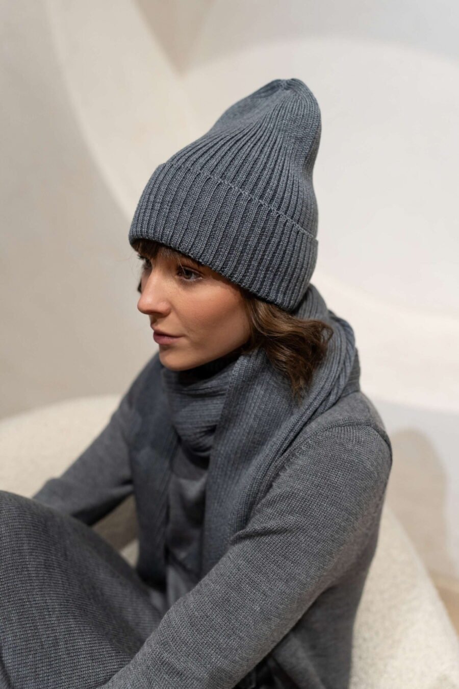 Grey ribbed beanie hat in merino wool. Paired with a matching scarf and a turtleneck dress.