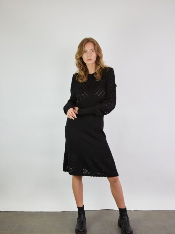 A lace dress in black merino wool. The dress features lace sleeves with ribbed cuffs