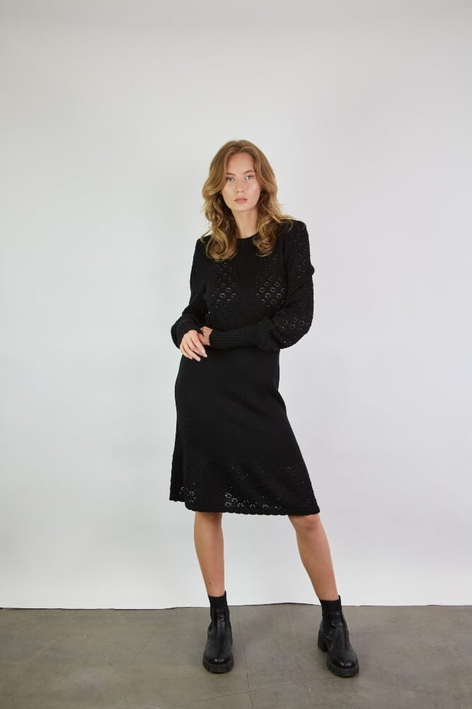 A lace dress in black merino wool. The dress features lace sleeves with ribbed cuffs