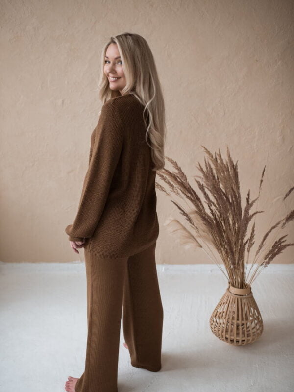 A blond girl wearing wide-leg trousers and a classic English rib cardigan in brown merino wool