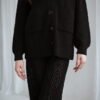 A girl wearing wide-leg trousers and a classic English rib cardigan in black merino wool