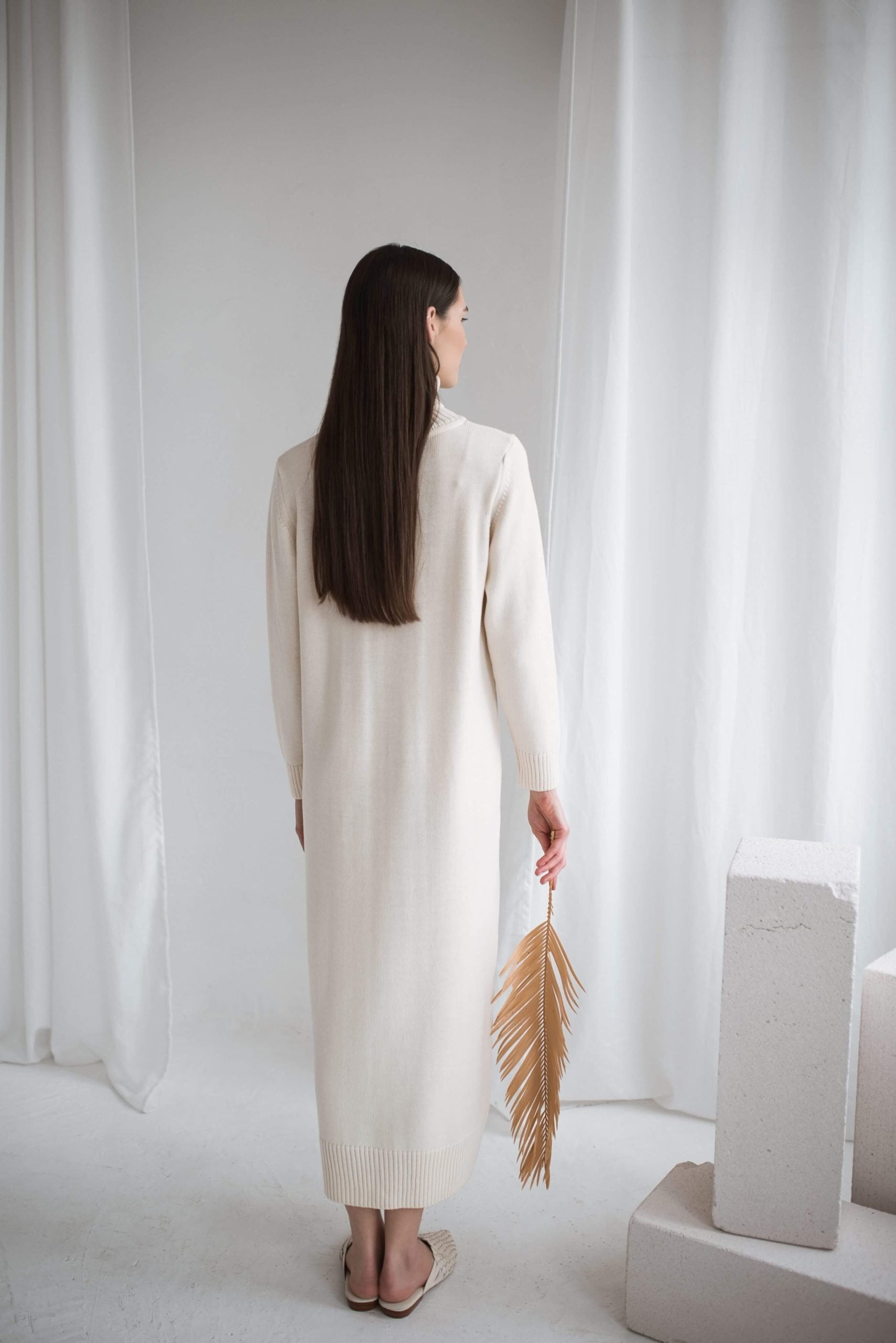 A long natural white merino wool dress with a roll neck and calf-length them